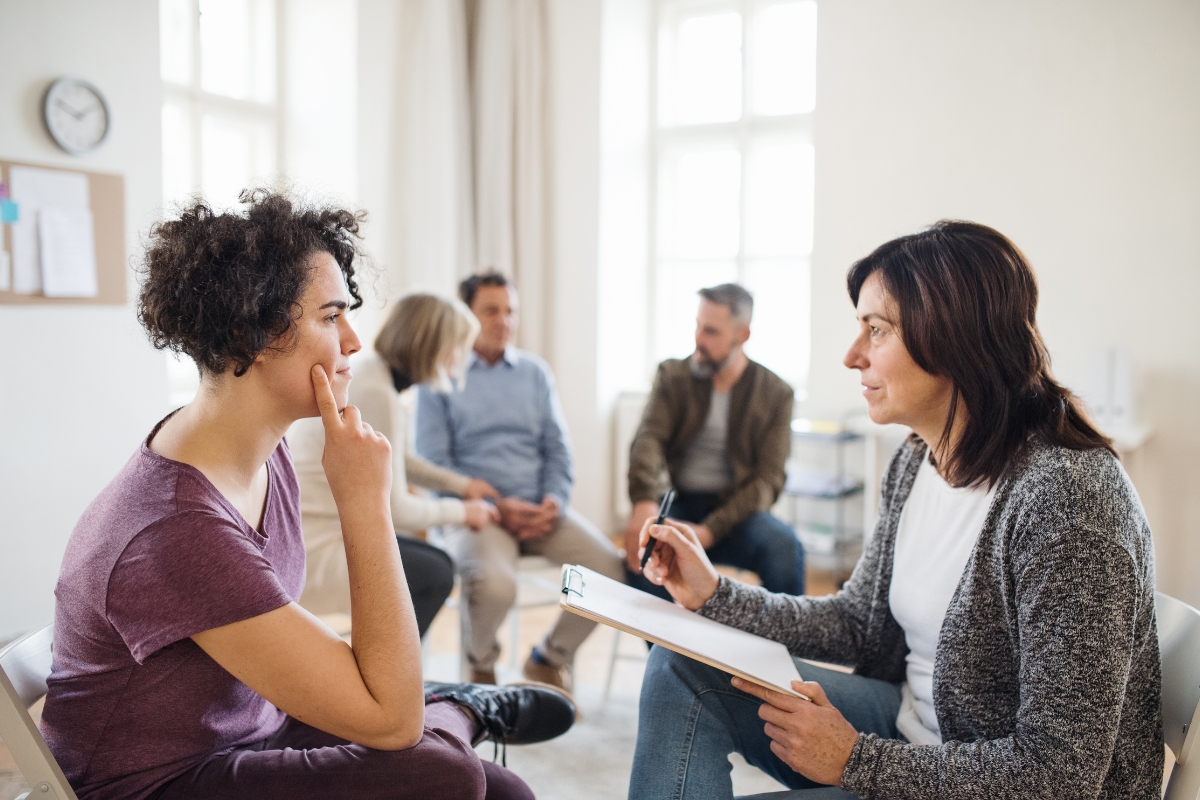 Therapist conducting anxiety counseling session with patient during group therapy in a mental health clinic